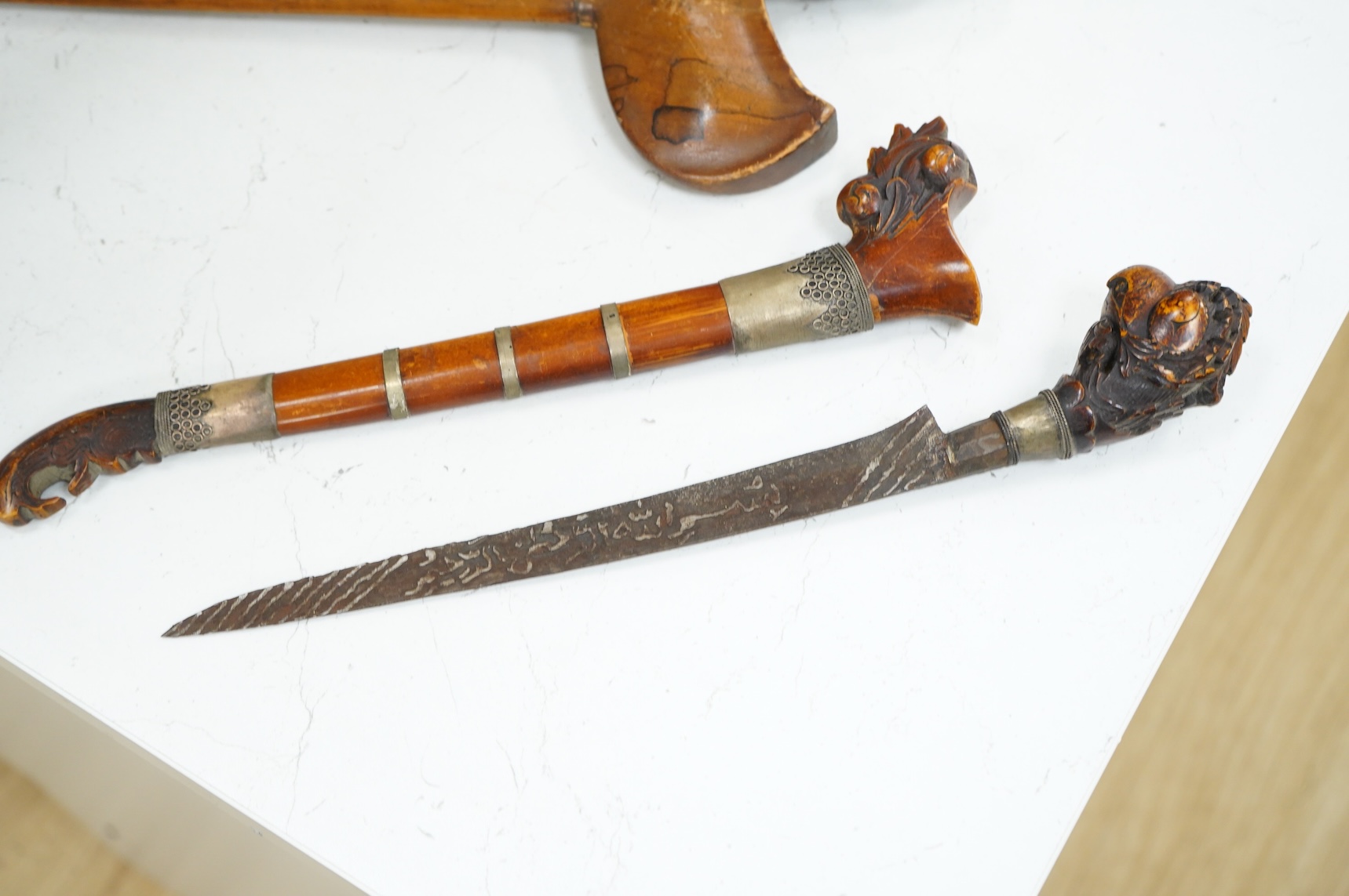 A Javanese dagger kris with straight pamor blade, wooden hilt carved as raksha, in its wooden sheath, together with a decorative dagger bade-bade, with etched blade